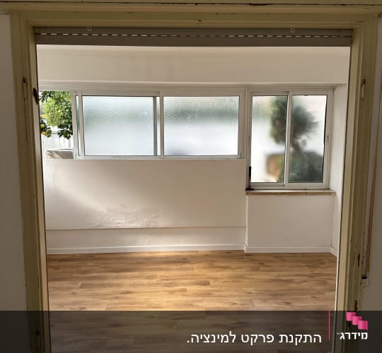 רצפת פרקט עץ בחדר מואר עם חלונות גדולים